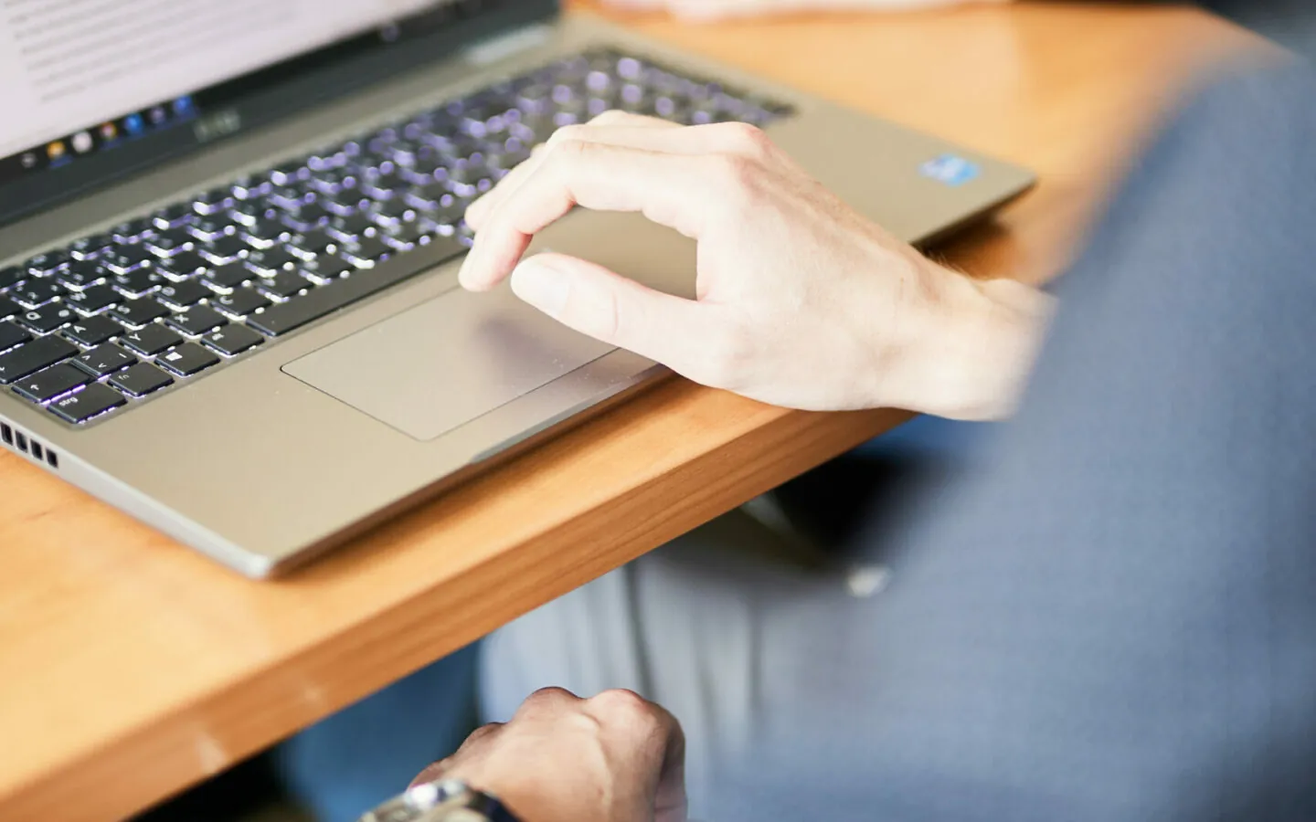Image of a laptop on a conference table with someone's hand resting on the keyboard.