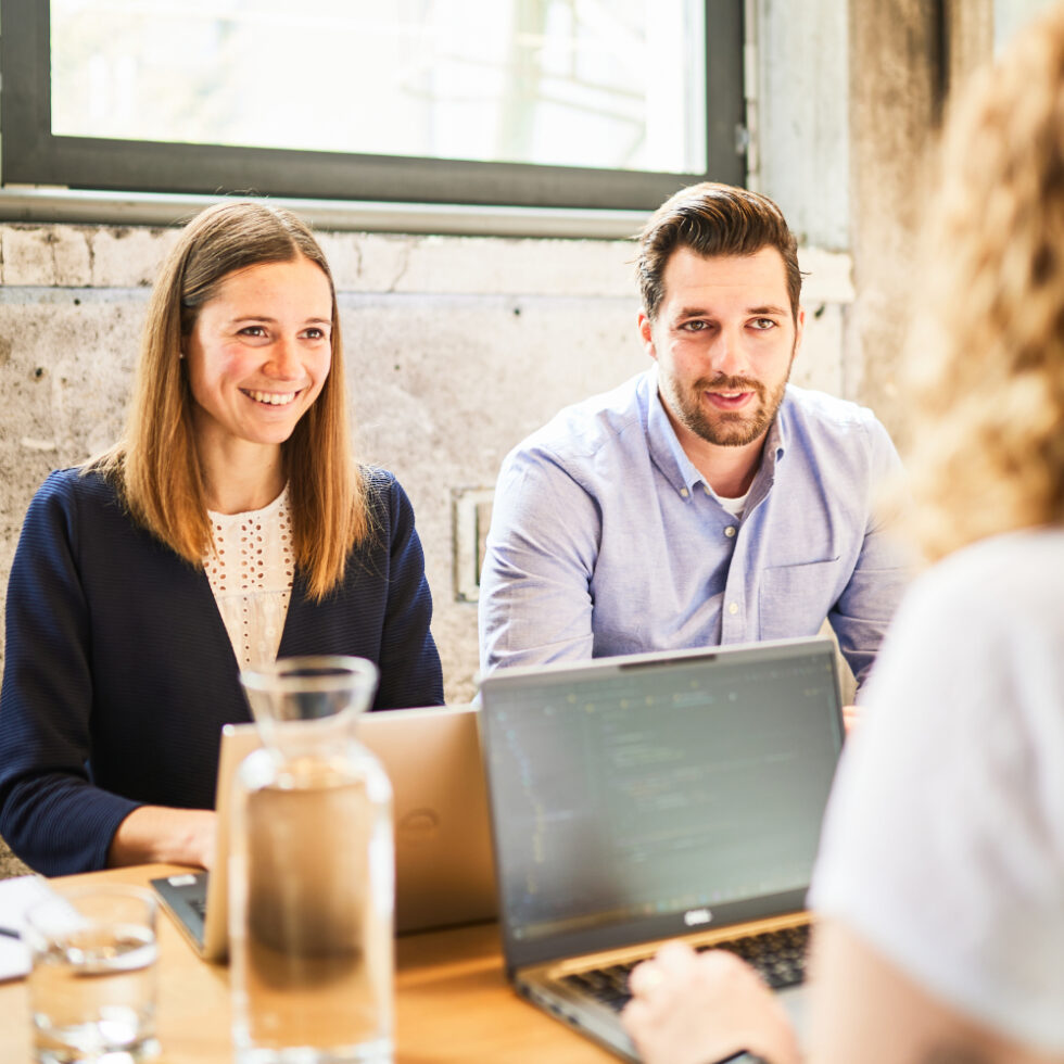 A man and a woman are listening attentively to a colleague.