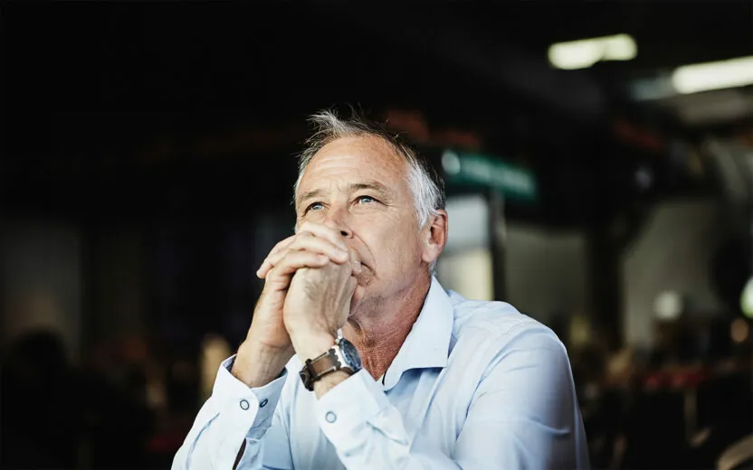 Ein Mann in eleganter Freizeitkleidung sitzt da und denkt über Lösungen nach.