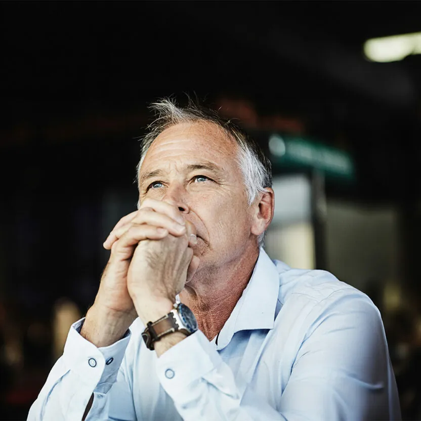 Man in smart casual clothing sits thinking hard about solutions.