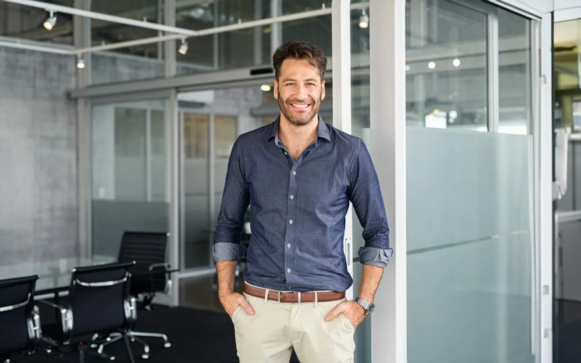 Portrait of a man with hands in pocket standing in an office while looking at camera. | IBM Planning Analytics