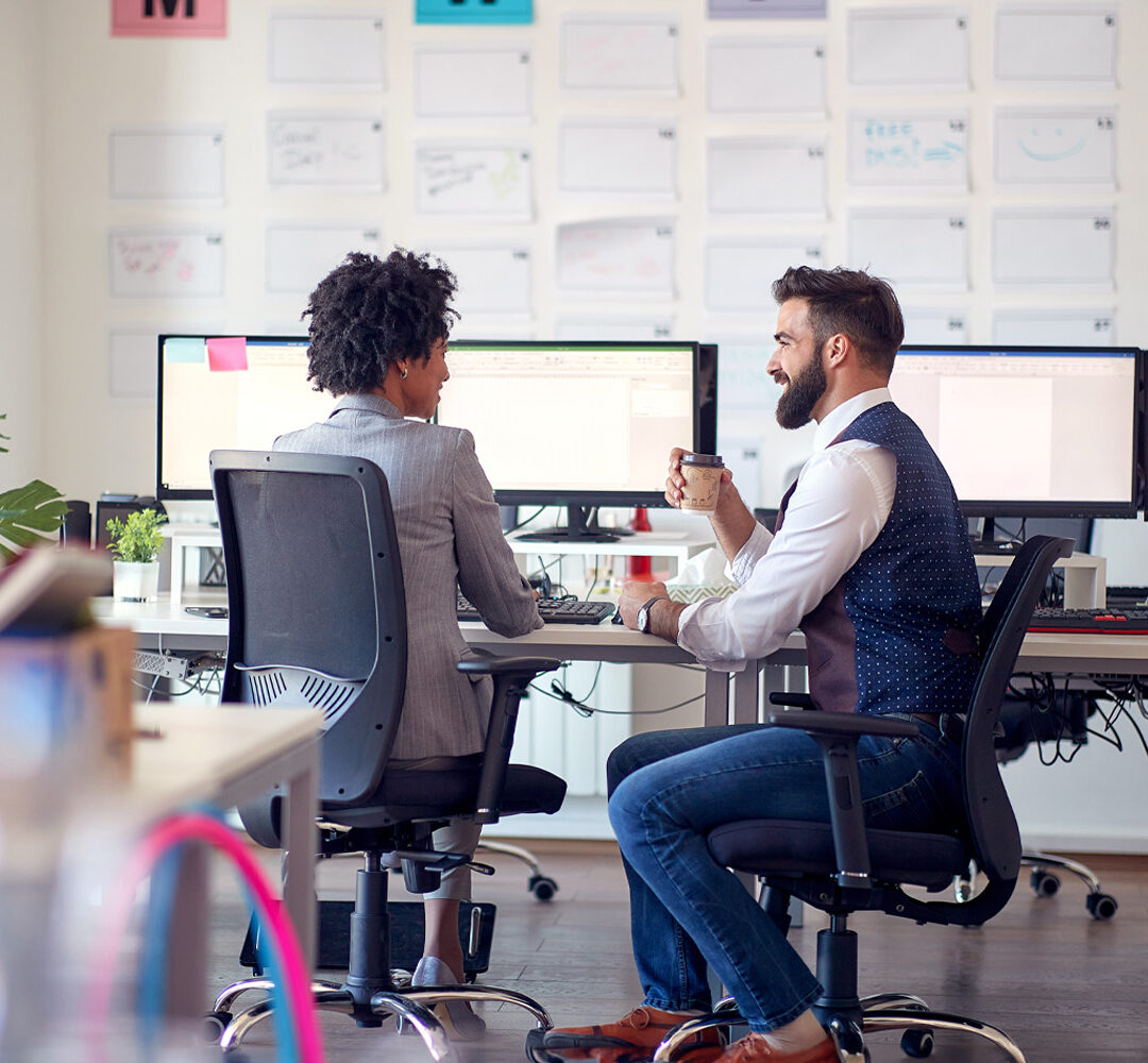 Two young business coworkers discussing together in the office