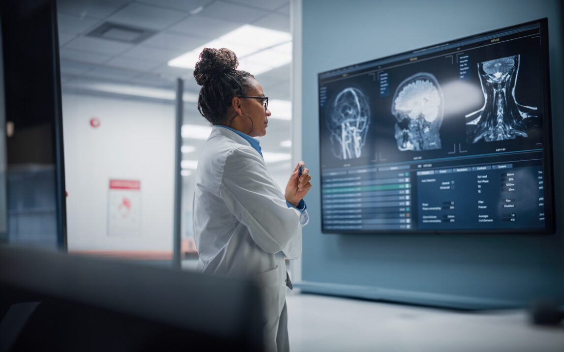Medical Science Hospital: Confident Female Neurologist, Neuroscientist, Neurosurgeon, Looks at TV Screen with MRI Scan with Brain Images, Thinks about Sick Patient Treatment Method. Saving Lives