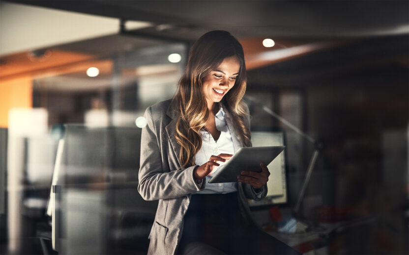 Cropped shot of a young attractive businesswoman using a tablet while working late at night in the office