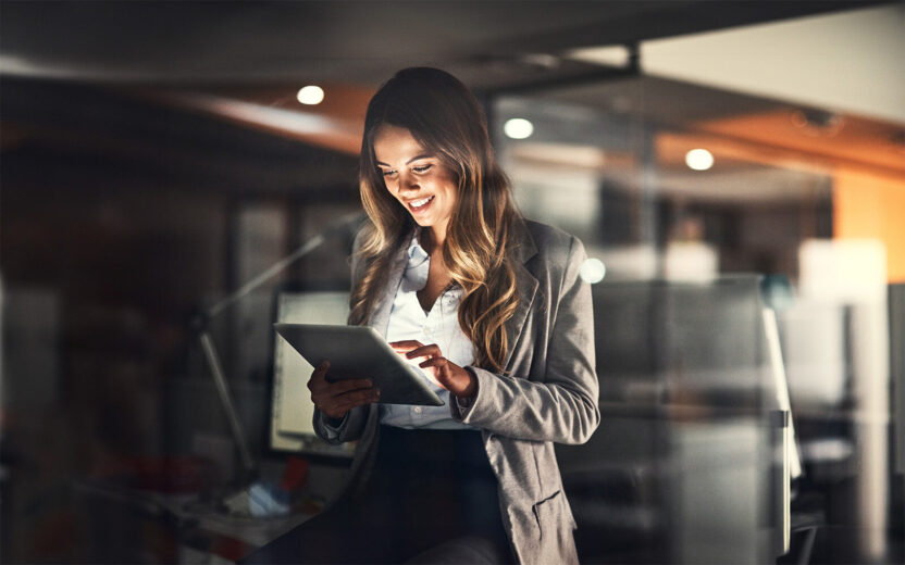 Cropped shot of a young attractive businesswoman using a tablet while working late at night in the office