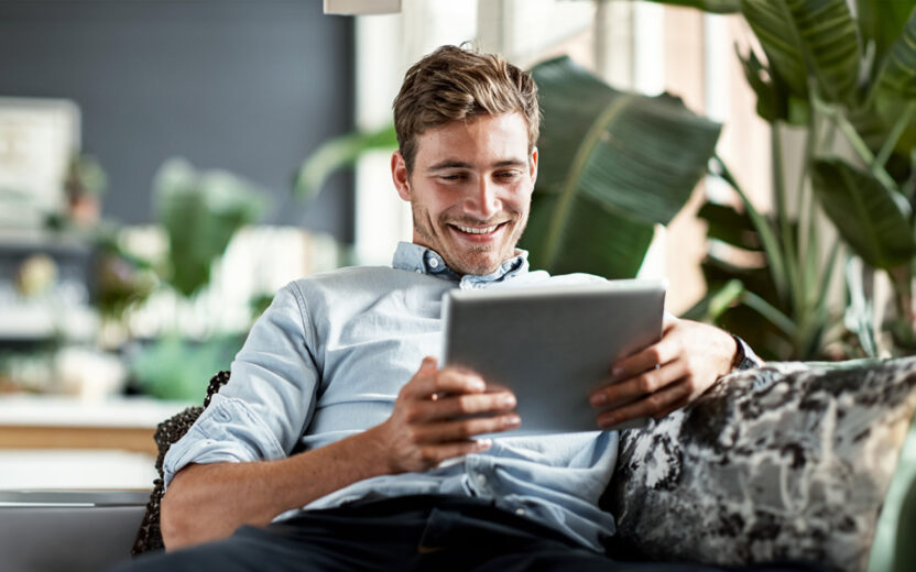 Shot of a happy young man using his tablet while relaxing on the couch at home
