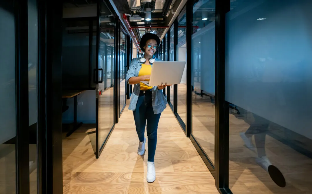 IT technician working late at the office using her laptop and smiling