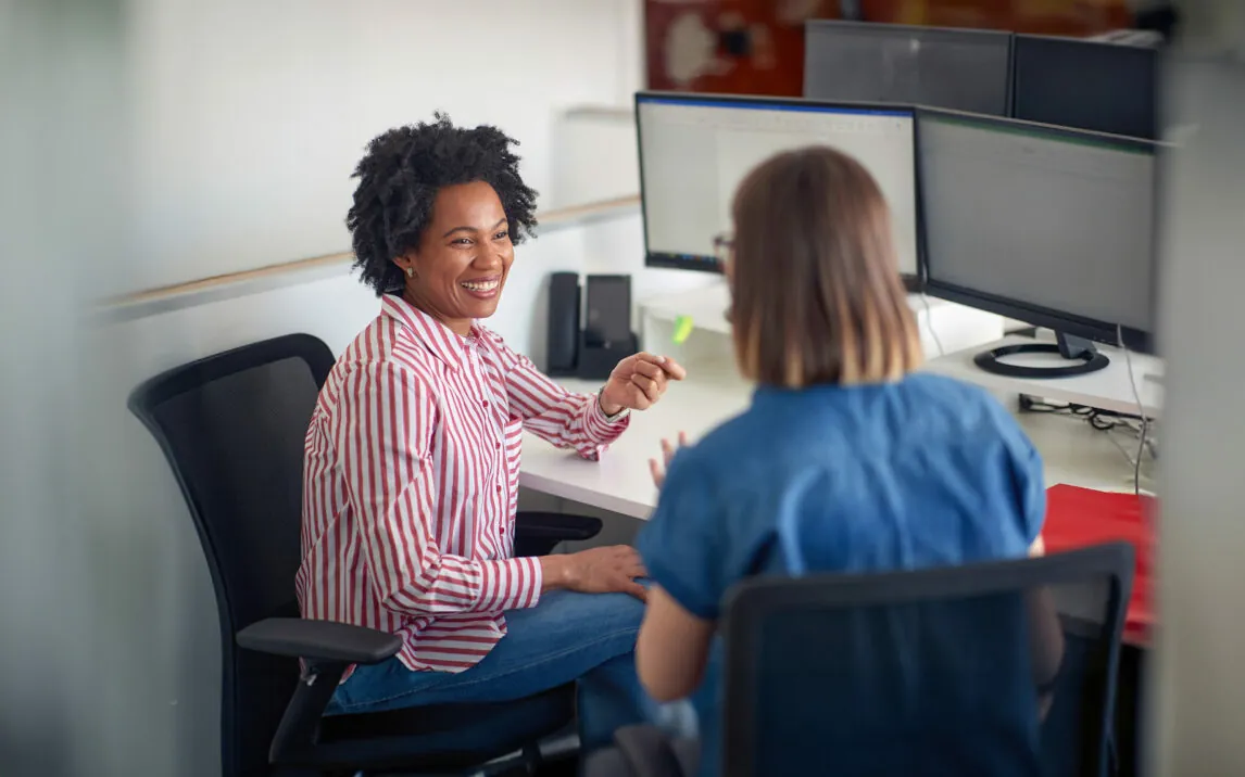 Two female coworkers consulting together in the office working on the project