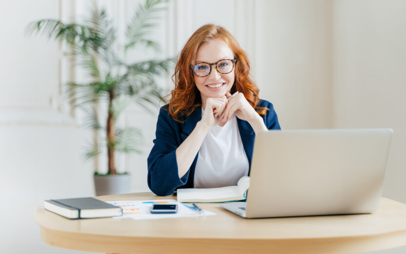 Smiling business woman sitting in front of Laptop