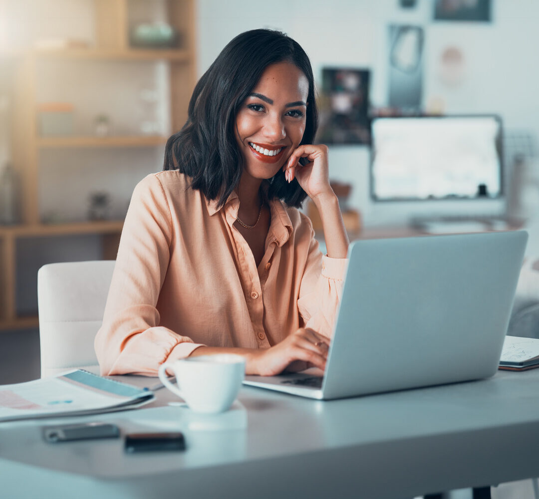 Portrait of a happy business woman working on her laptop at a desk in the office