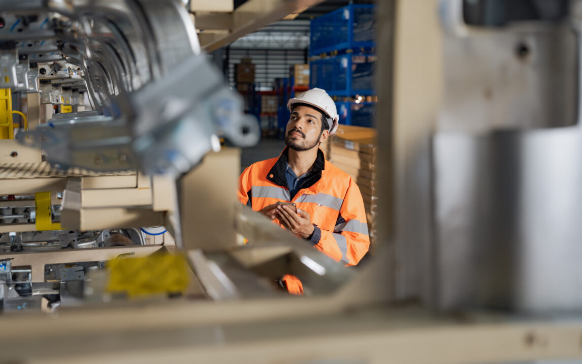 Young man industrial engineer wearing a white helmet while check the welding on the production line in the factory.
