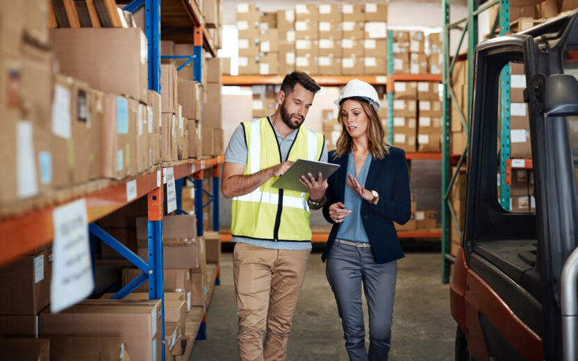 Cropped shot of an attractive young businesswoman walking through a warehouse with a male worker