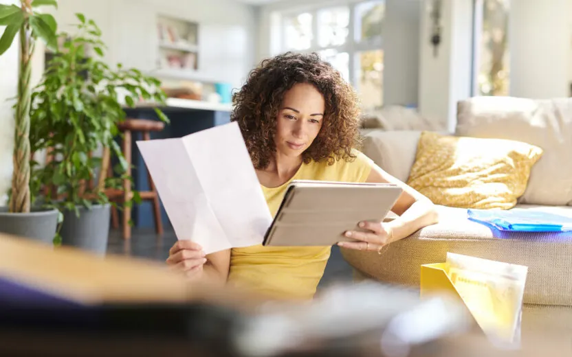 Woman reading on tablet and holding a letter with her other hand