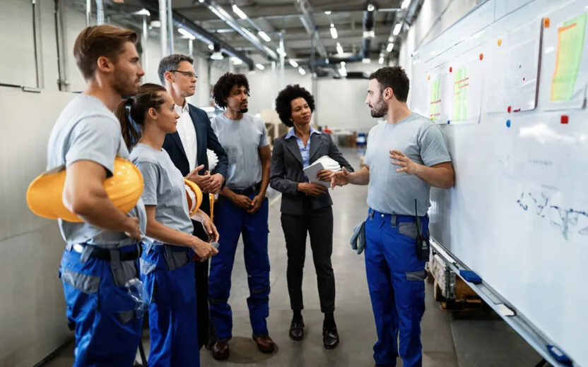 Young worker giving presentation in front of whiteboard in a factory