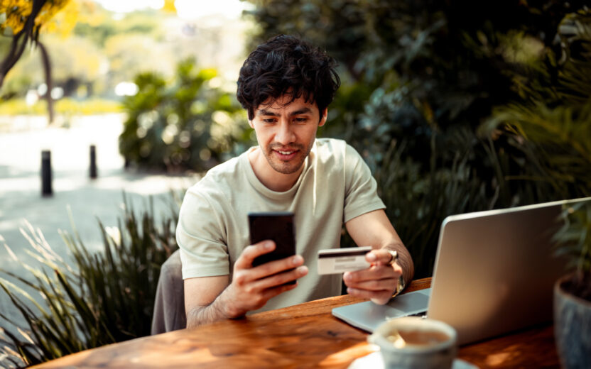 Young man sitting at the cafe and paying online with credit card