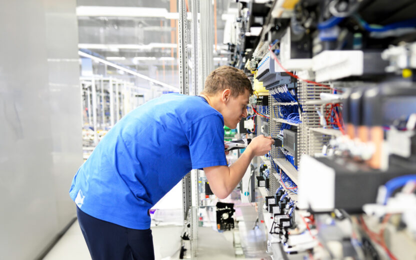 Young apprentice worker in an industrial company assembling electronic components in the mechanical engineering of a modern factory