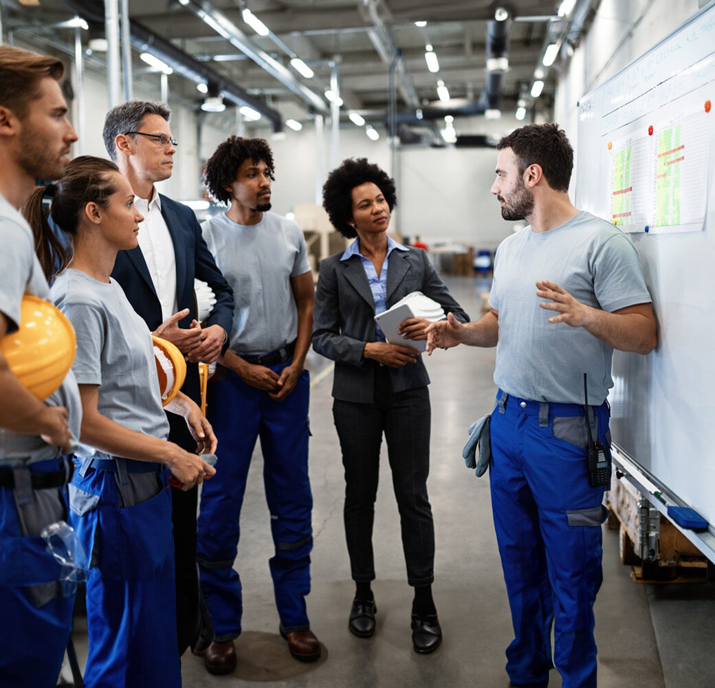 Young worker giving presentation in front of whiteboard in a factory