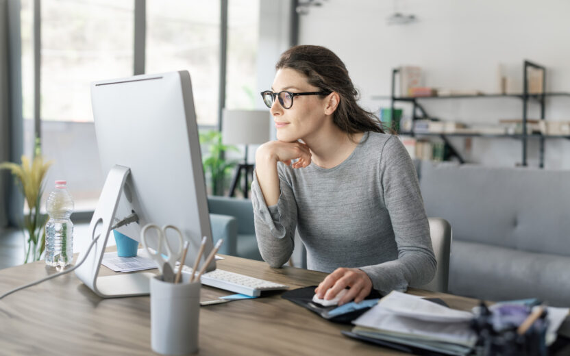 Professional woman sitting at desk and connecting with her computer, she is working from home