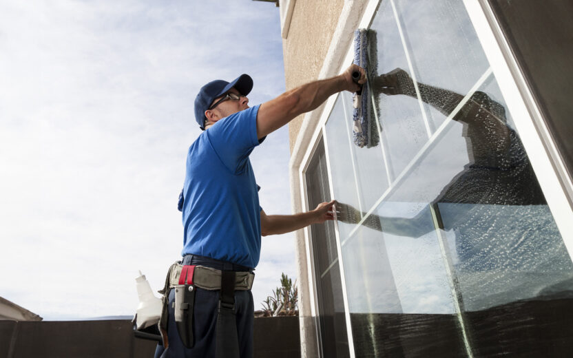 Homem a limpar as janelas de uma casa