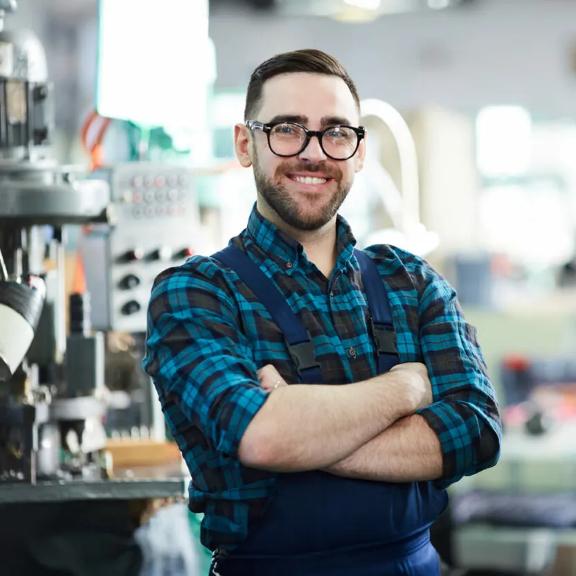 Factory worker looking at camera while posing in workshop standing with arms crossed