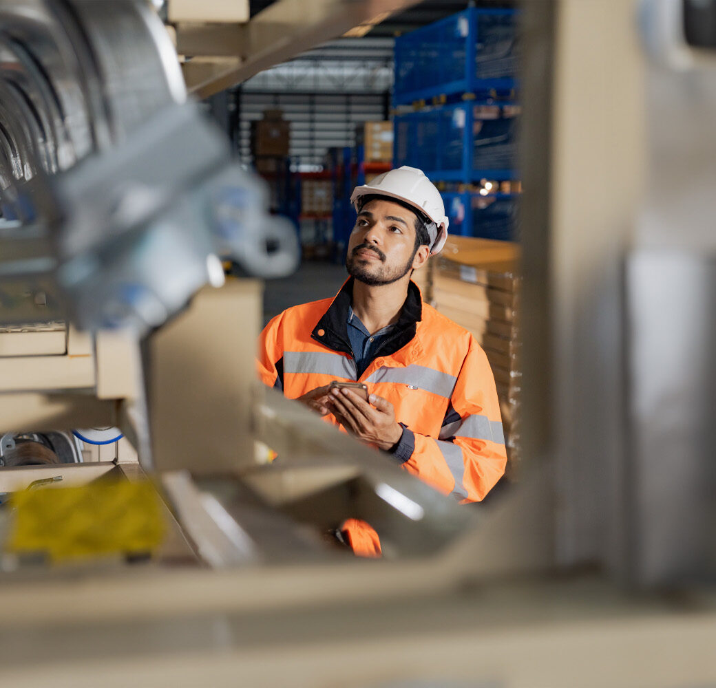 Young man industrial engineer wearing a white helmet while check the welding on the production line in the factory with intracompany processes.