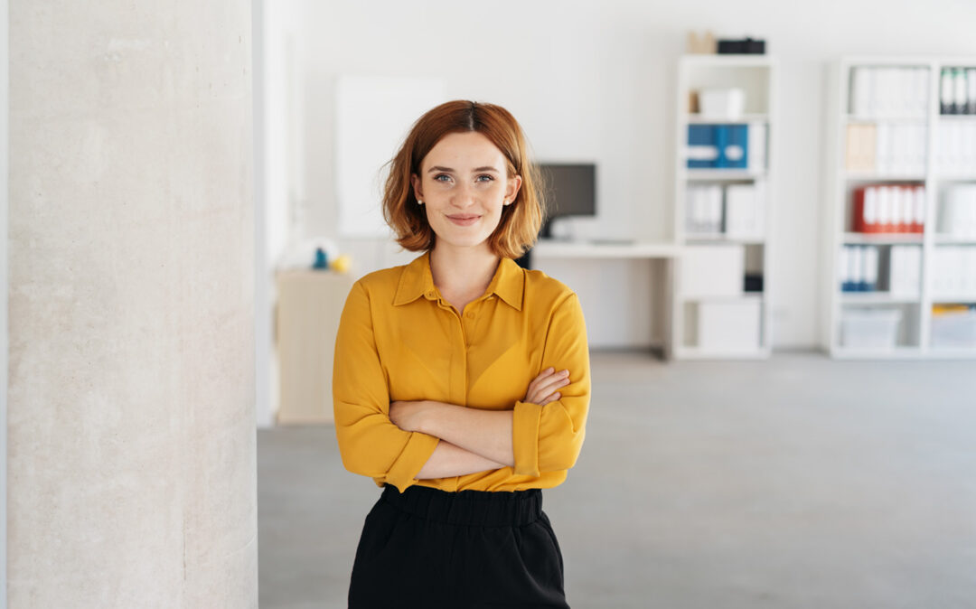 Happy, relaxed, confident businesswoman with folded arms, smiling in a spacious office.
