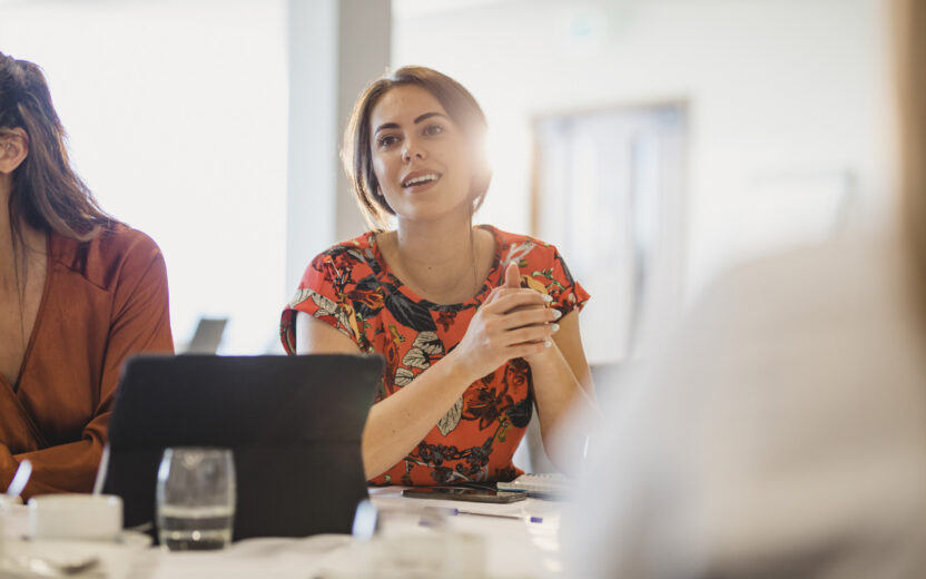 Female employee sitting at meeting table looking thoughtful, ideas, strategy, focus