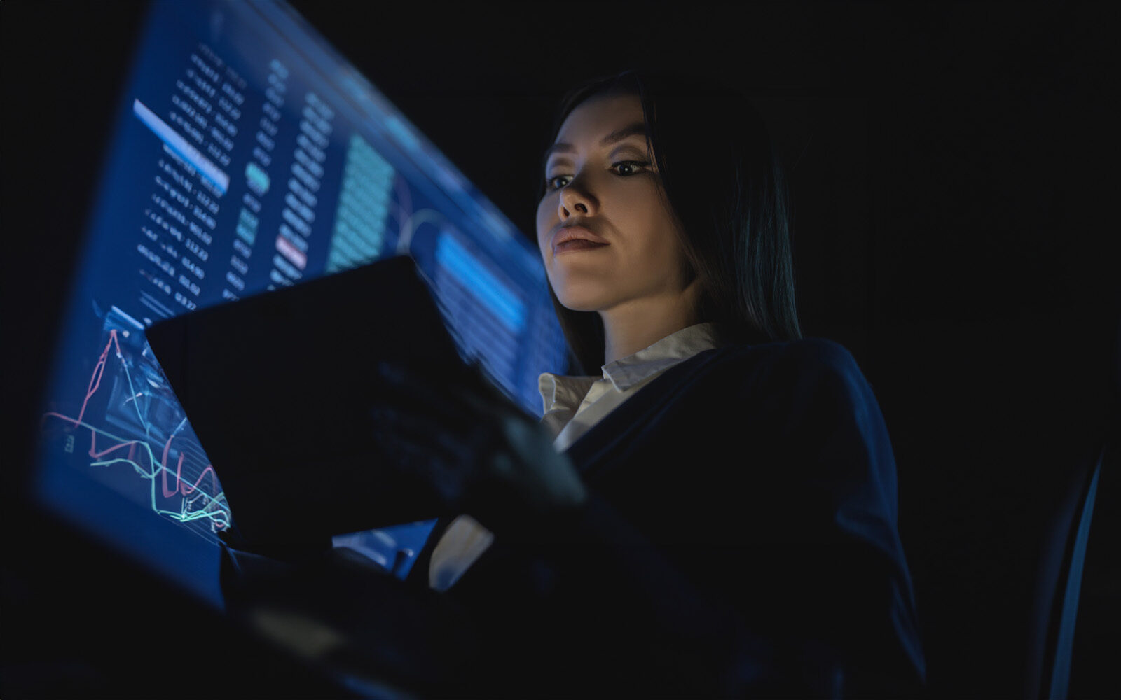 A business woman holding tablet in the dark office