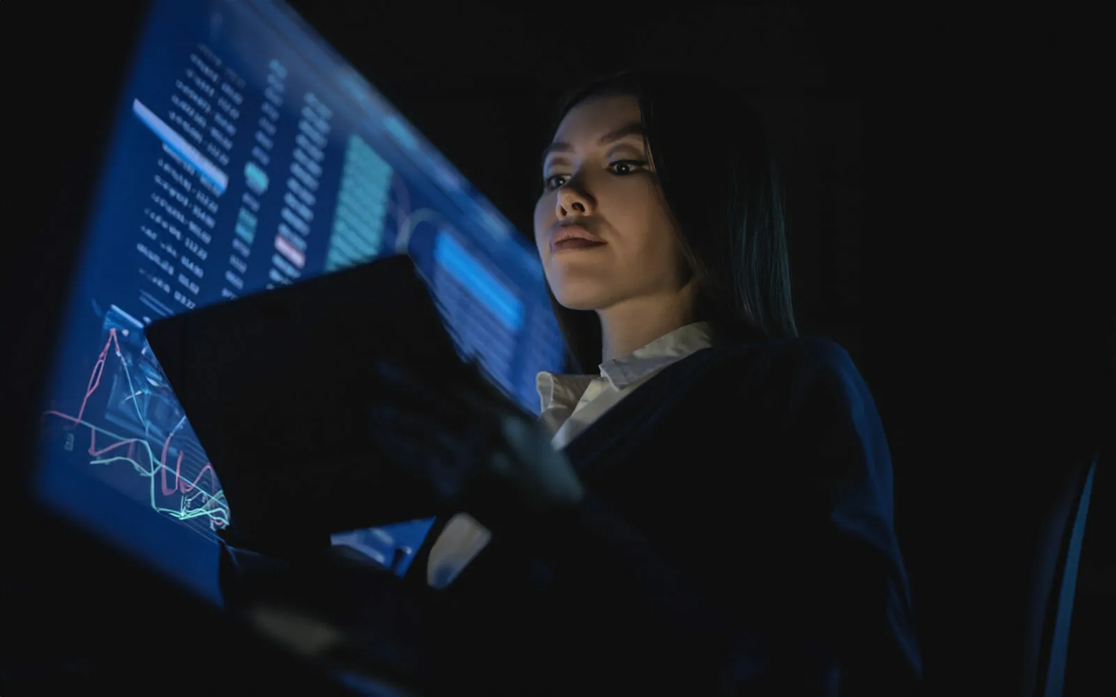 A business woman holding tablet in the dark office