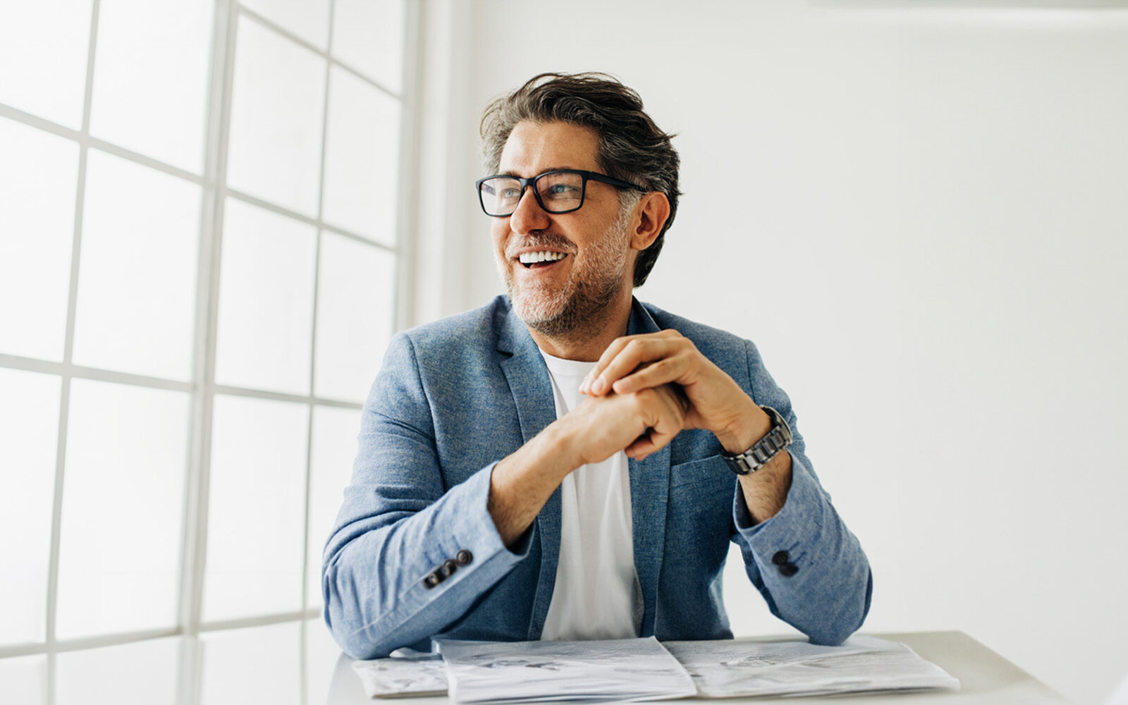 Business man looking outside the window in an office. Senior business man thinking about work while sitting at his desk in a suit.