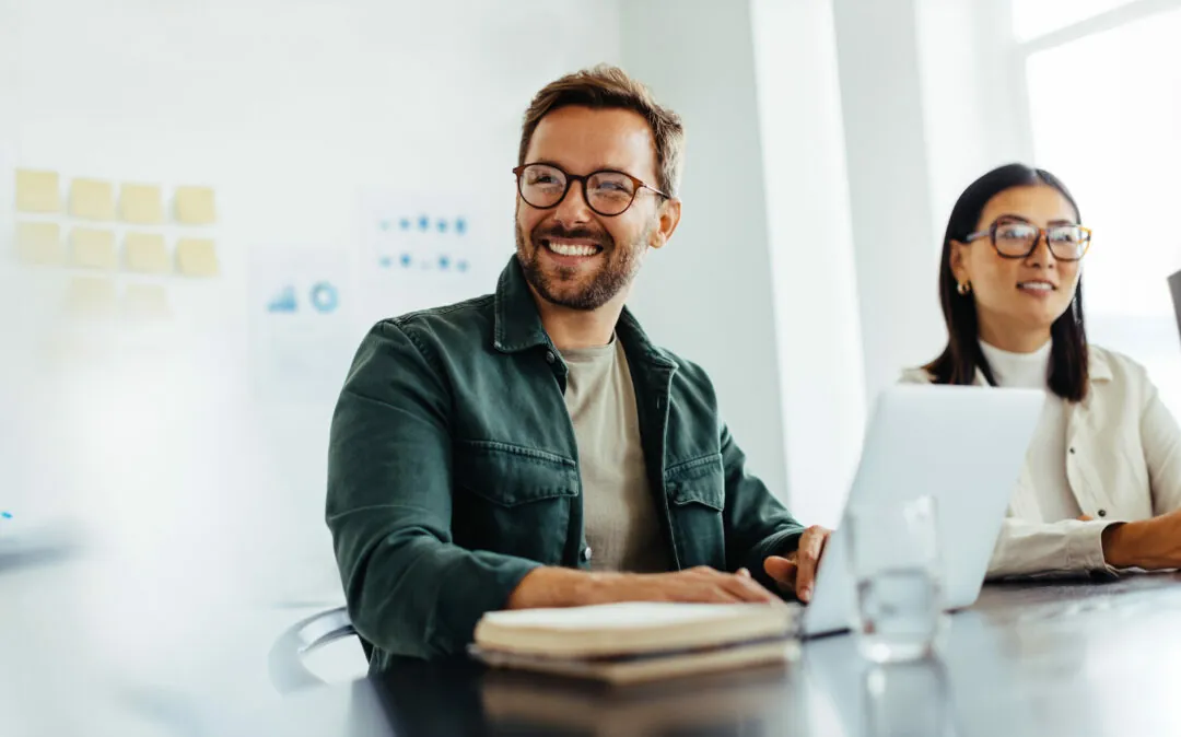 Homem de negócios feliz a ouvir uma discussão numa sala de reuniões de um escritório. Profissional de negócios sentado numa reunião com os seus colegas.