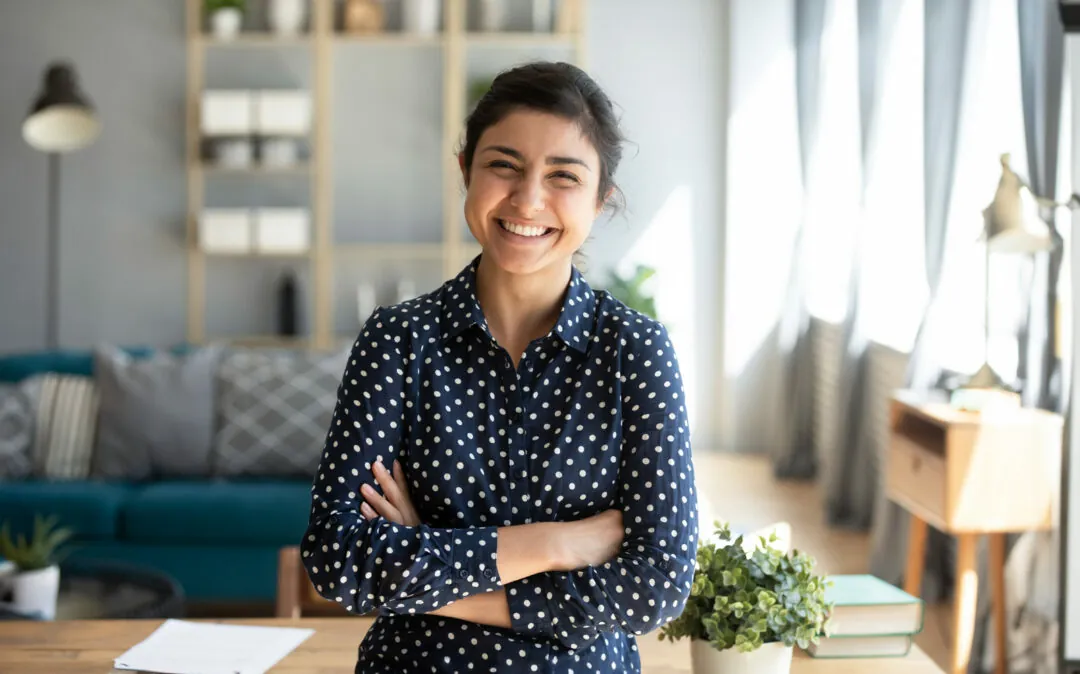Mulher, de braços cruzados, a olhar para a câmara e a sorrir
