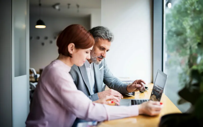 A man and woman having business meeting in a cafe, using laptop.