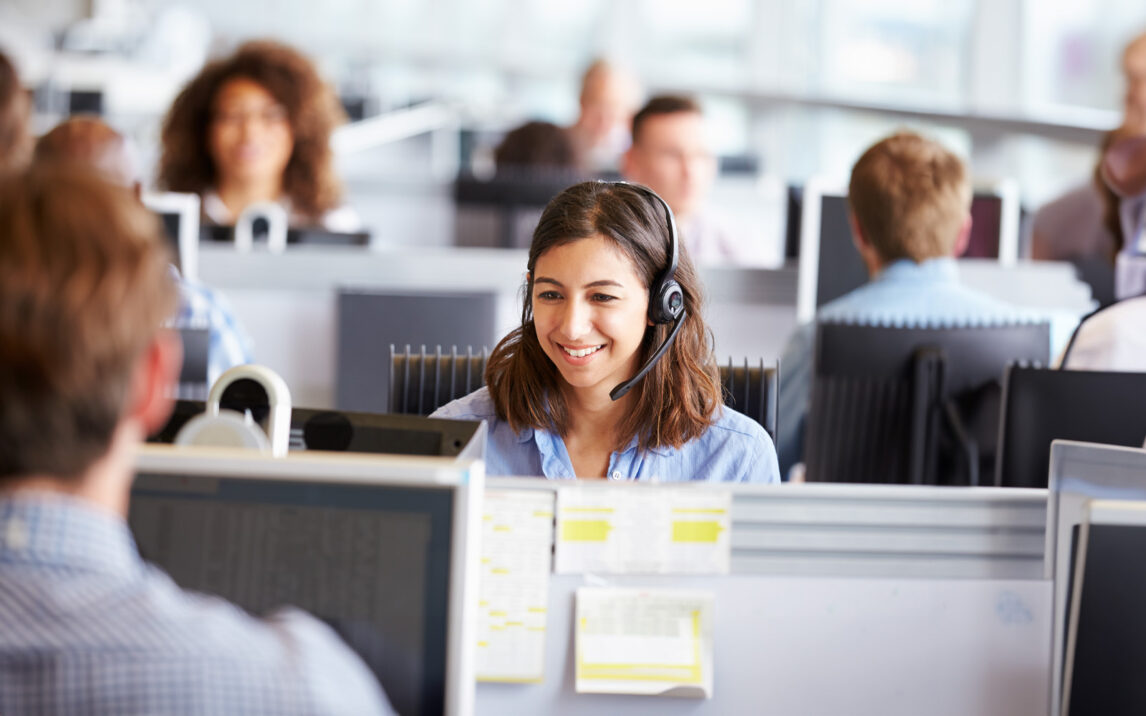 Young woman working in call center, surrounded by colleagues