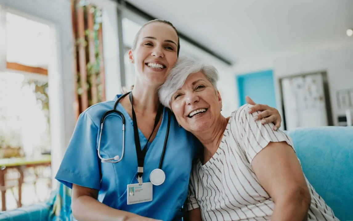 Home carer hugs elderly patient.