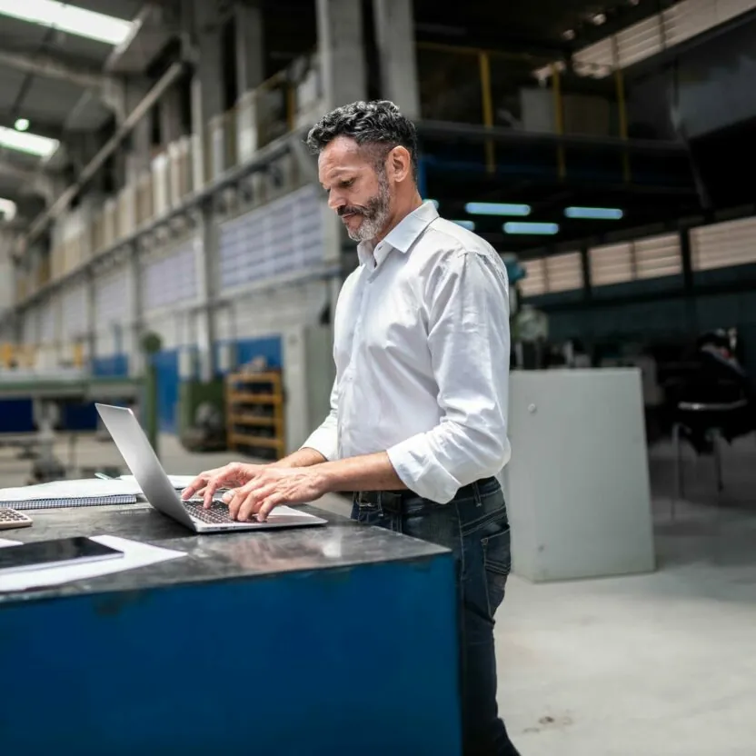 Mature businessman using laptop in a factory