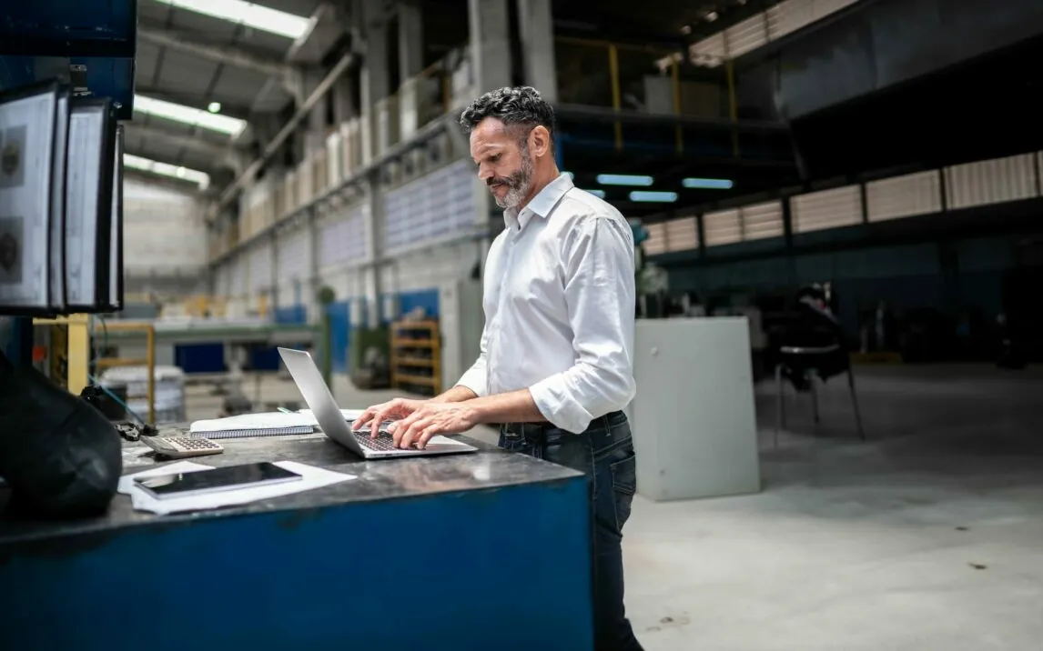 Mature businessman using laptop in a factory