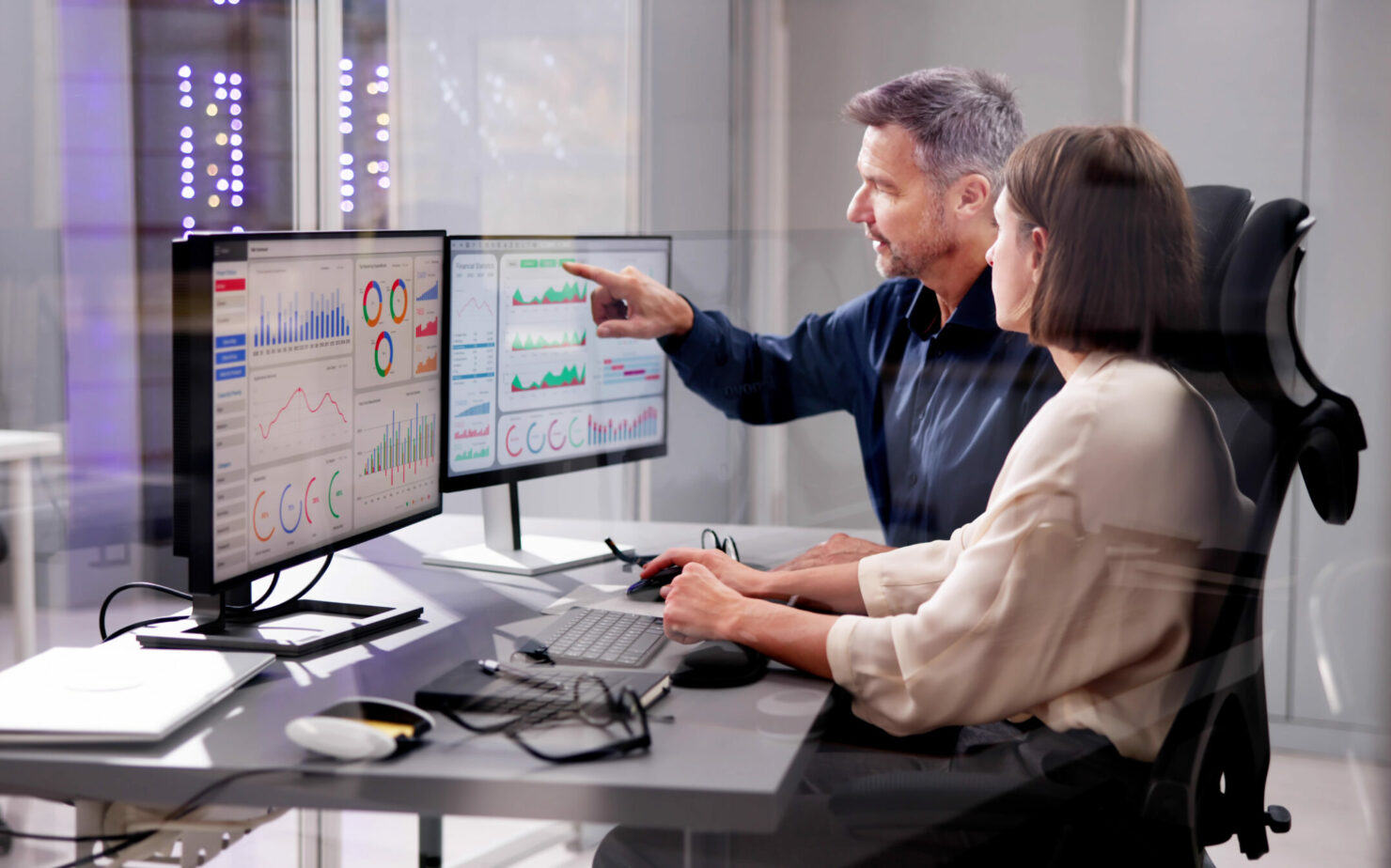 Woman and men are analyzing a dashboard on a monitor.