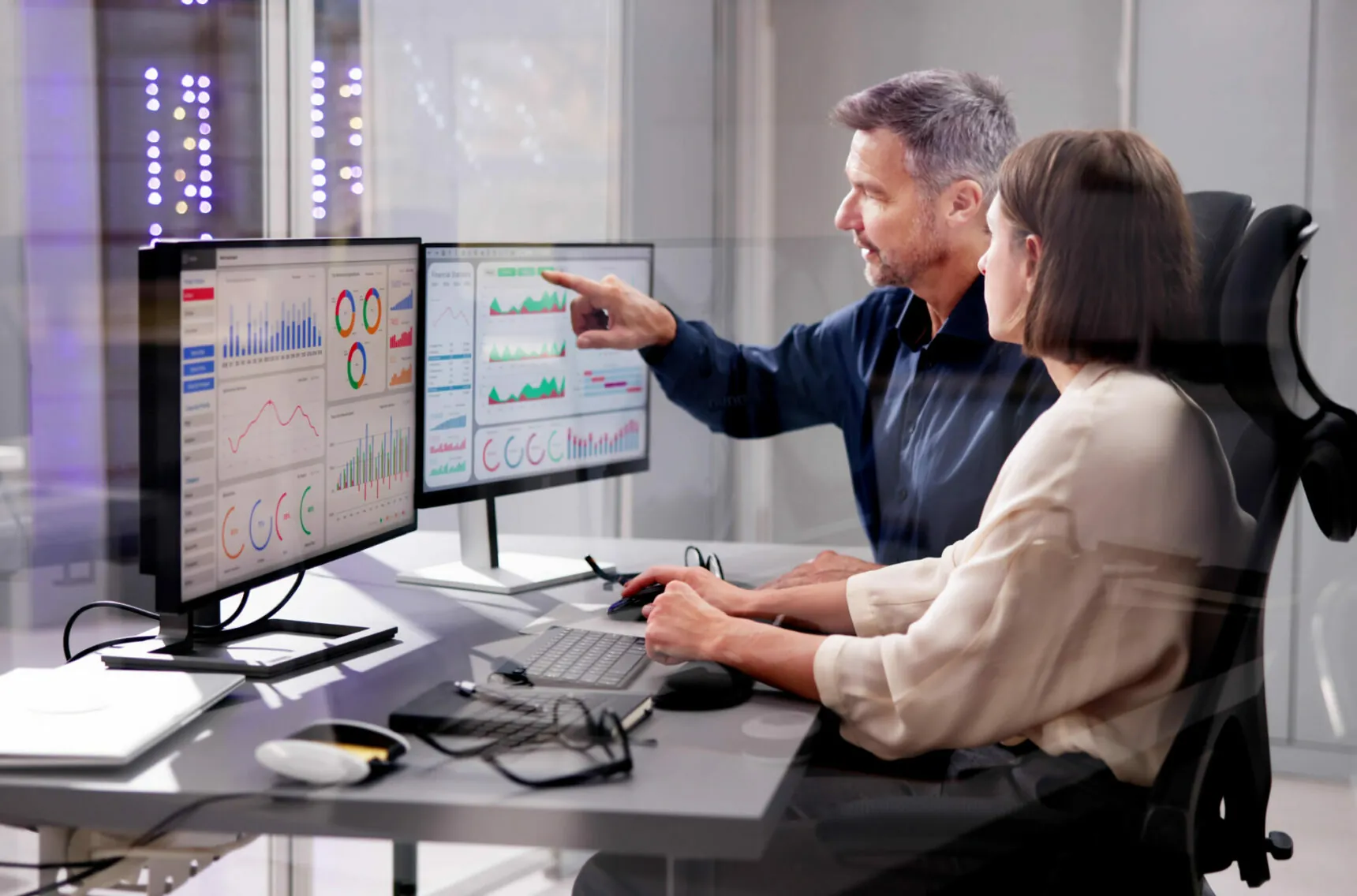 Woman and men are analyzing a dashboard on a monitor.