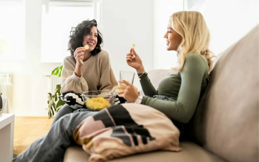 Friends sitting on sofa eating potato chips