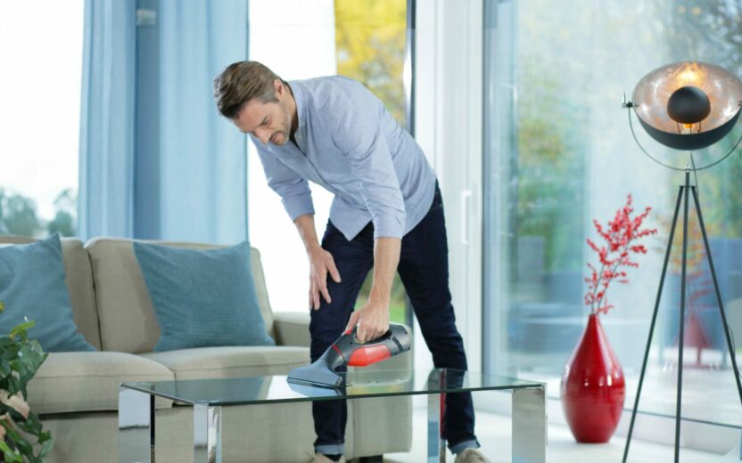 Man cleans table with window vacuum cleaner