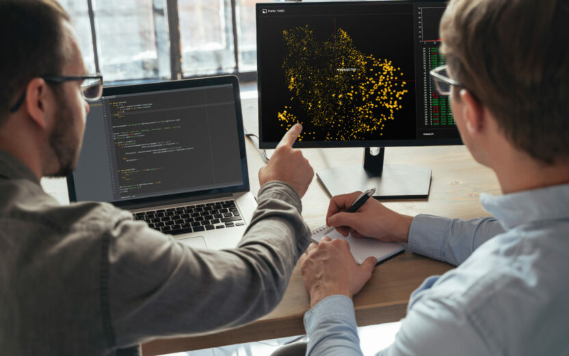 Nahaufnahme von zwei Männern, die als Data-Science-Spezialisten im Büro zusammenarbeiten und große Daten auf dem Bildschirm analysieren. Programmierer arbeiten an einem neuen Projekt
