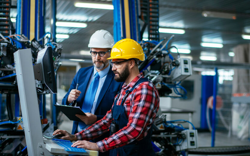 Two men in production hall looking at a PC