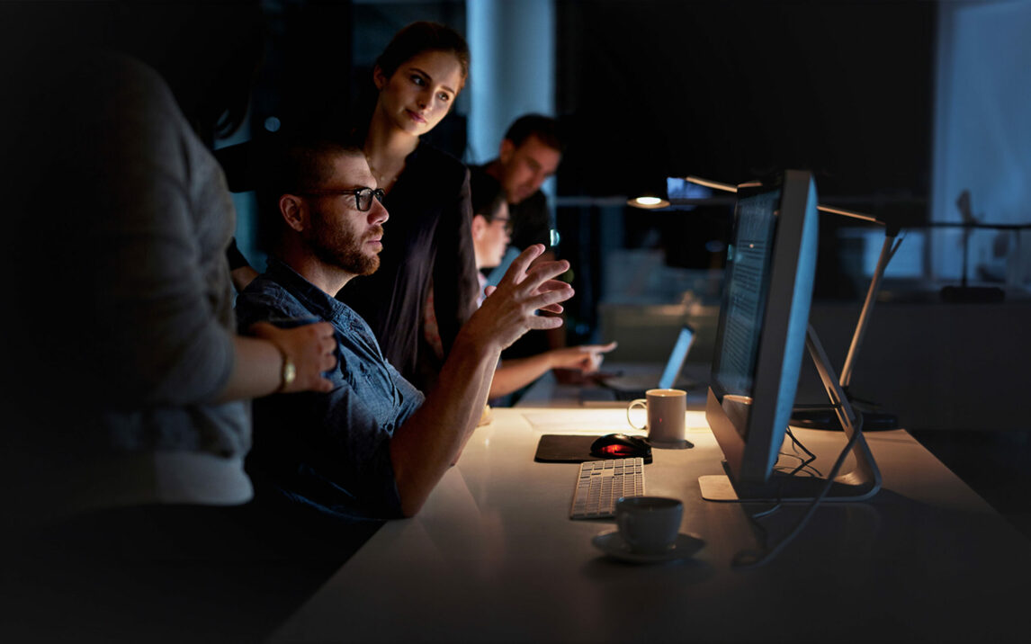 Shot of a group of colleagues using a computer together during a late night at work