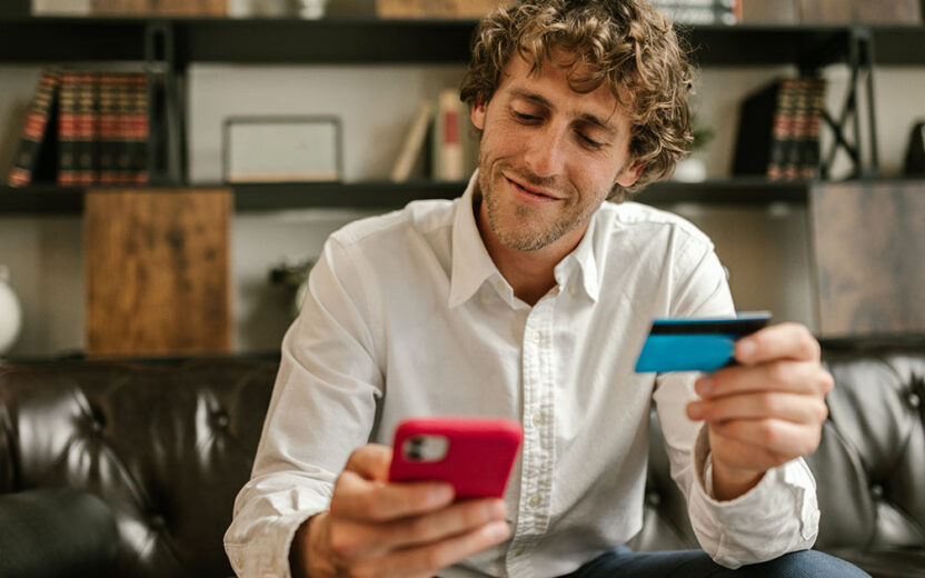Mann hält eine Kreditkarte und Smartphone in der Hand
