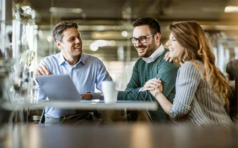 Man presenting a plan on a computer to young couple during a meeting in the office.