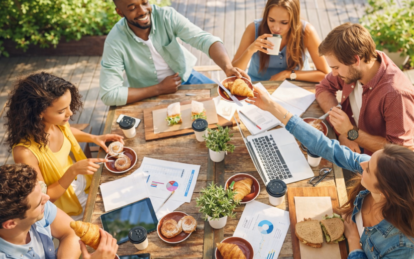 6 Personen, die mit Laptop am Tisch sitzen und frühstücken | Agentic AI Summer Brunch