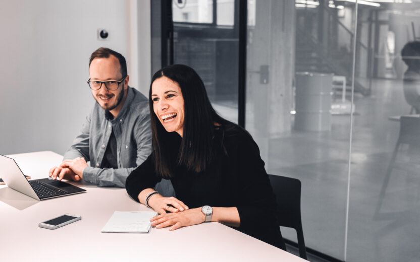 Zwei valantic Austria Mitarbeiter*innen, die zusammen in einem Meeting-Raum sitzen.