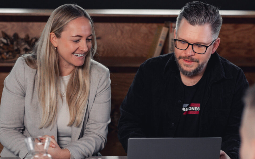 2 valantic Austria Mitarbeiter*innen, die an einem Holztisch sitzen und arbeiten