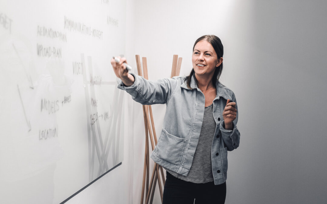 Junge Frau präsentiert Projetkidee an einem White Board.